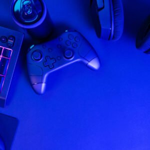 Flat lay shot of purple lit keyboard by various modern wireless gadgets and copyspace on blue desk